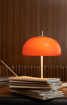 Pomarańczowa lampa stojąca na biurku.